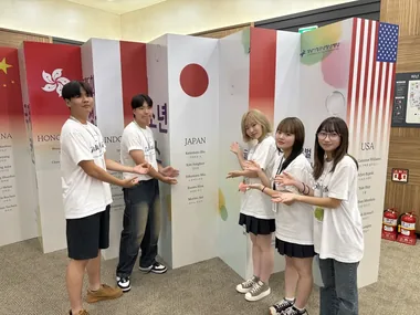 各国の国旗の展示の前で笑う生徒たち